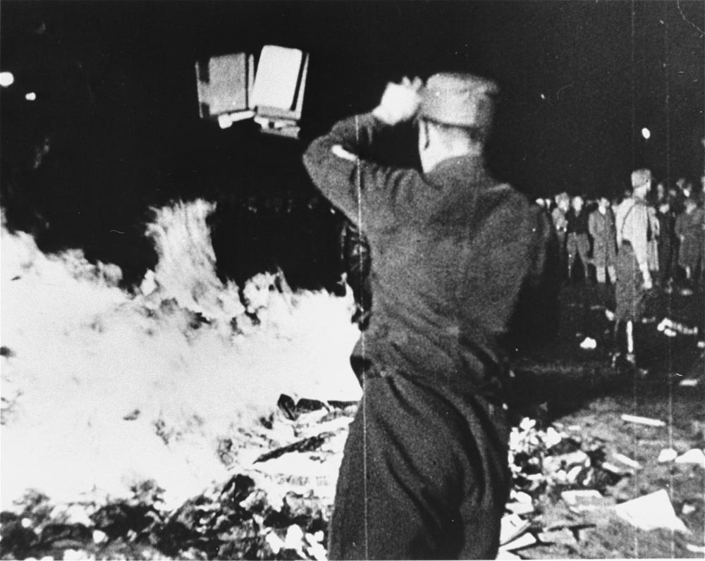 A member of the SA throws confiscated books into the bonfire during the public burning of "un-German" books on the Opernplatz in Berlin.